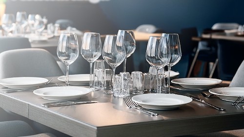 Gedeckter Küchentisch mit Tellern, Gläsern und Besteck